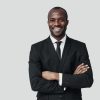 handsome-young-african-man-formalwear-looking-camera-smiling-while-standing-against-grey-wall